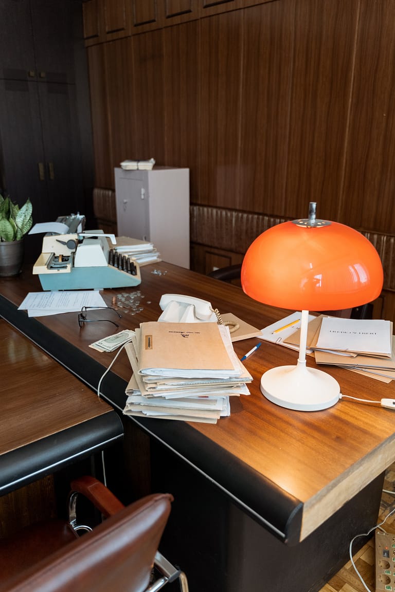 A wood desk with many files and an orange lamp, representing the need for documents to get pre-approved.